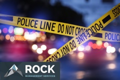 Yellow law enforcement tape isolating crime scene. Blurred view of city street, toned in red and blue police car lights